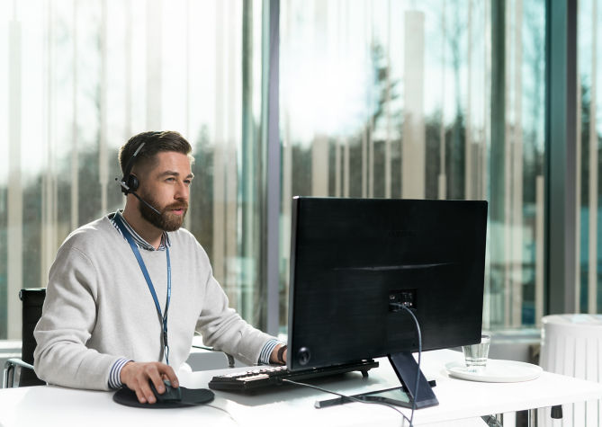 Hombre con auriculares frente a una computadora - KONE Servicio al cliente